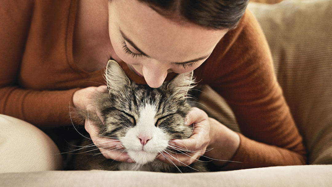 Vrouw leunt over kat voor een kus