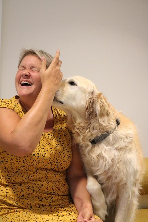 een patiënte lacht met een golden retriever