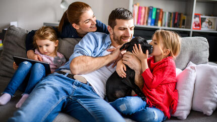 Une famille de quatre personnes jouant avec un chiot noir