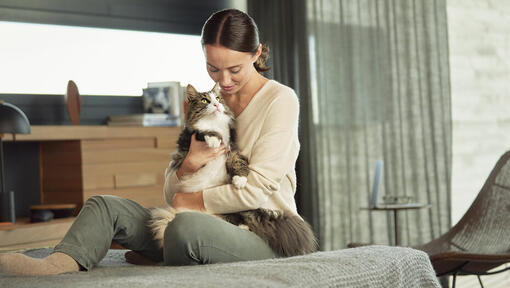 Vrouw zittend op het bed kat knuffelen