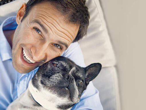 Homme heureux et son chien bulldog dans ses bras