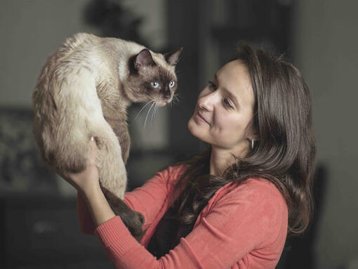 une femme tenant un chat gris