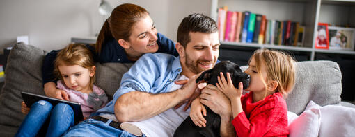 Une famille de quatre personnes jouant avec un chiot noir